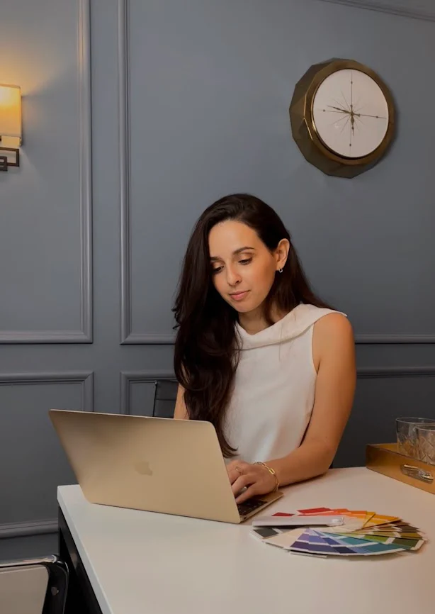 Hannah from Curate your style a white woman sat at a desk with laptop and colour chart