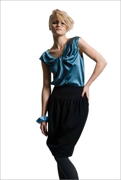 model wears a black skirt and tights with teal silk camisole