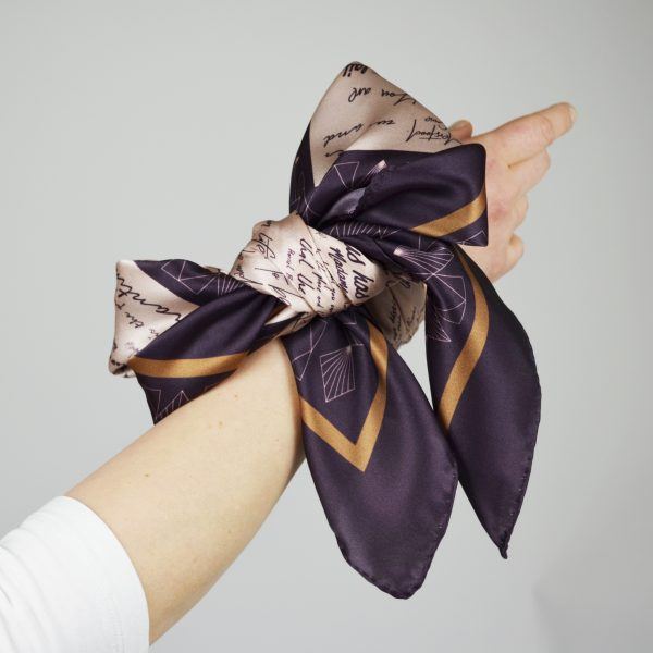 Pink and burgundy scarf tied onto wrist in a large bow