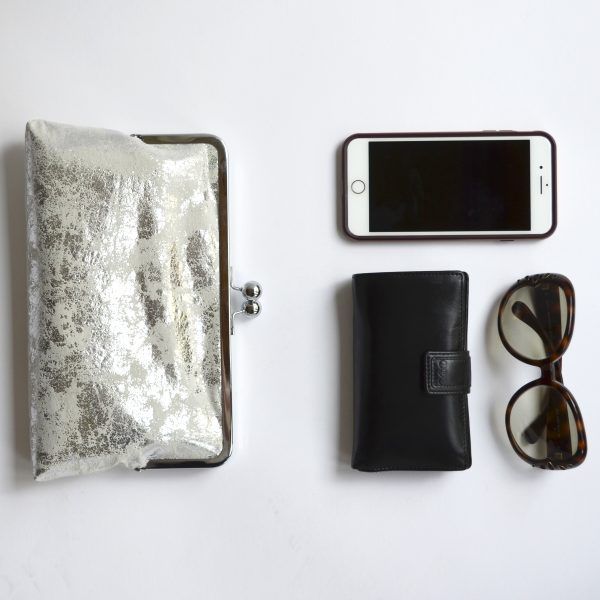 Flatlay with silver clutch bag, wallet, sunglasses and i-phone