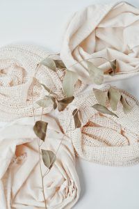 bundles of cream fabric with a dried bunch of leaves on top
