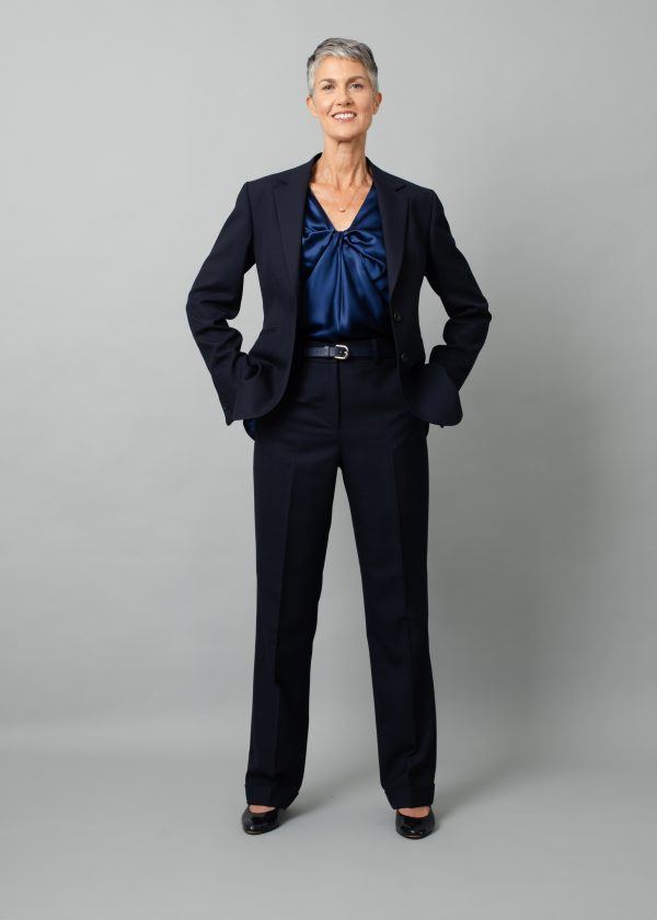 White woman with short grey hair modelling navy trouser suit and blue silk top