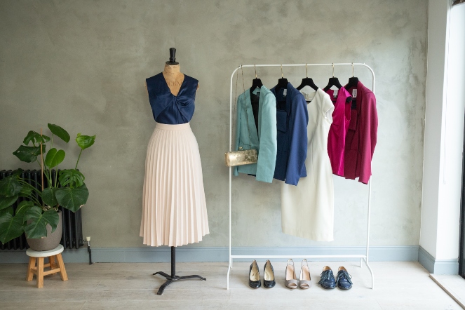 Dara Ford tailored outfits with a skirt and camisole on a dressmakers dummy jackets a camisole and a dress hanging on a rail a clutch bag and pairs of shoes