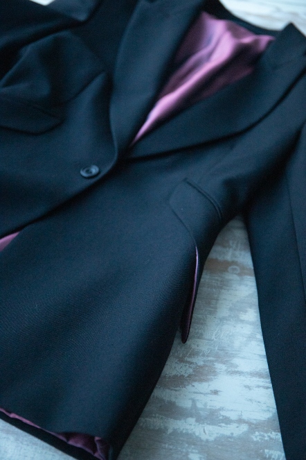 Close up of a tailored black jacket with purple silk lining