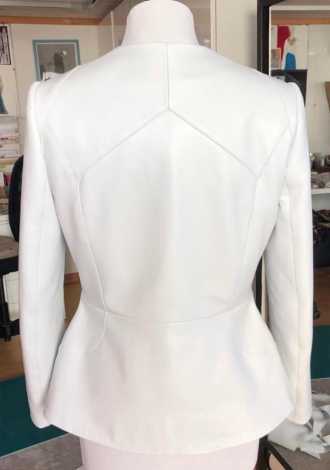 Image showing the back of a white tailored jacket for women with fitted waist and shoulder seams