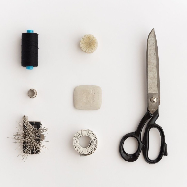 Flat lay of dressmakers accessories Cotton pins thimble wax chalk tape measure and scissors