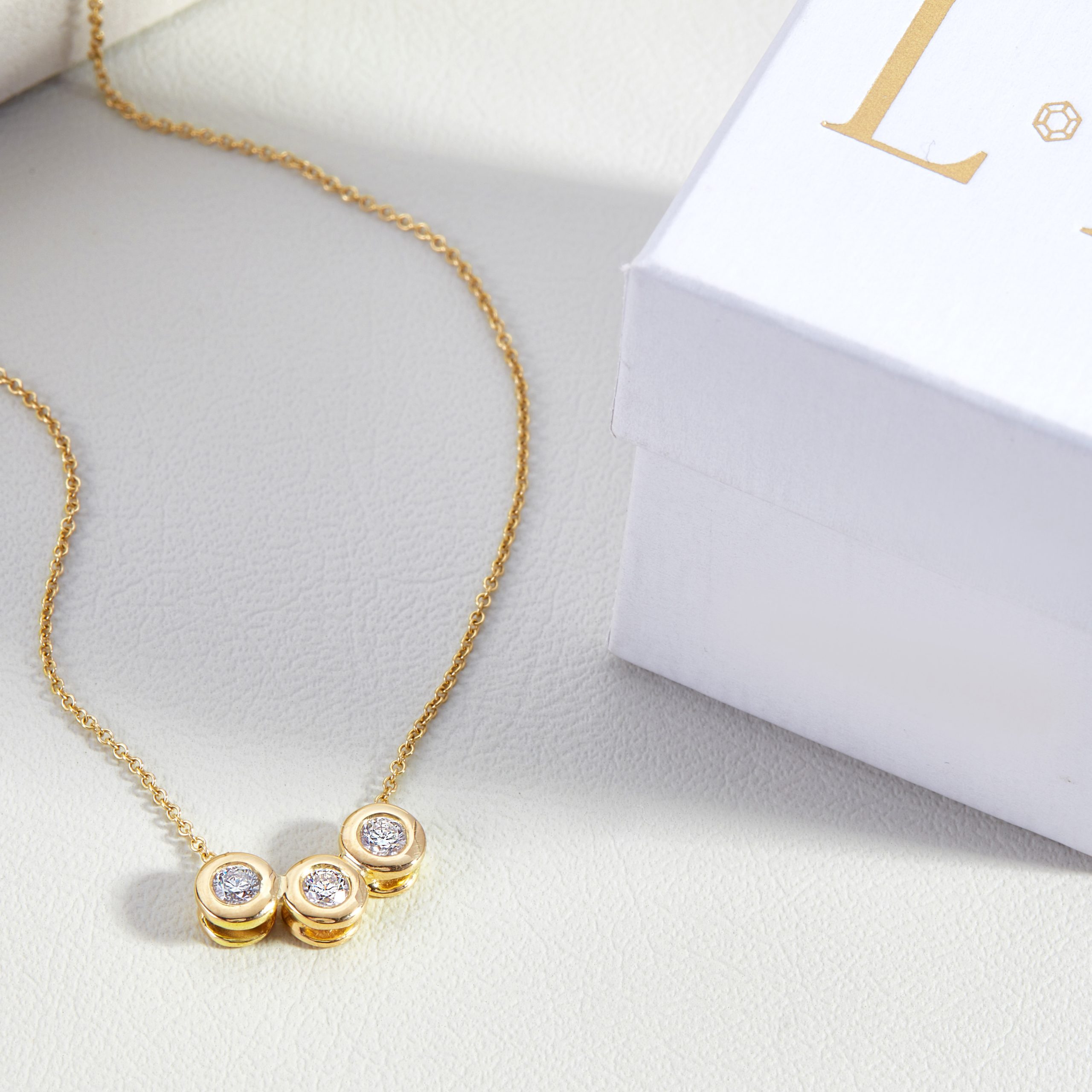 Gold necklace with three small circles containing diamonds.