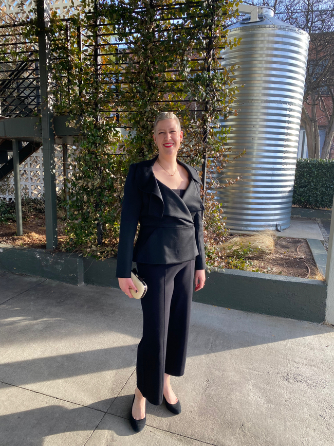 A white woman wearing a tailored black trouser suit