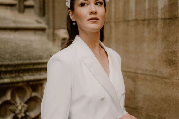A white, brunette bride wearing a tailored ivory blazer dress, and a bridal hairpiece